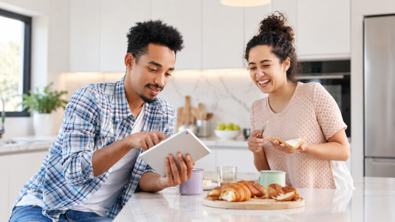 Couple reviewing home-buying finances on a tablet in their kitchen